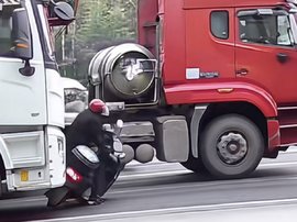 男子骑车横穿货车流 被撞倒后推行十几米！